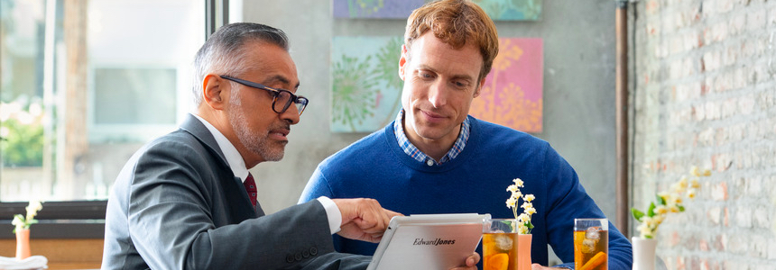 A financial advisor holding a tablet device speaks to a man.