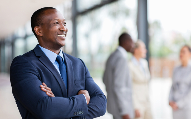A smiling man with arms crossed peers out an office window.