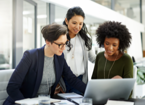 Three women looking at a laptop computer.
