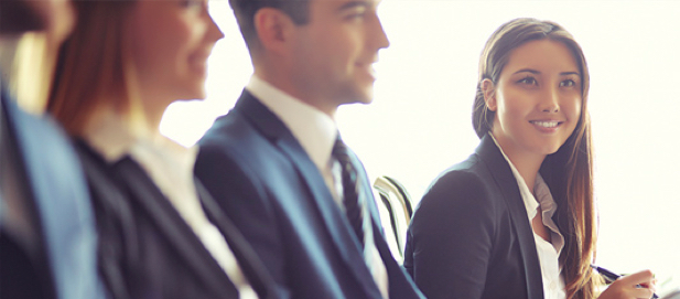 A businesswoman and three associates seated at a table.